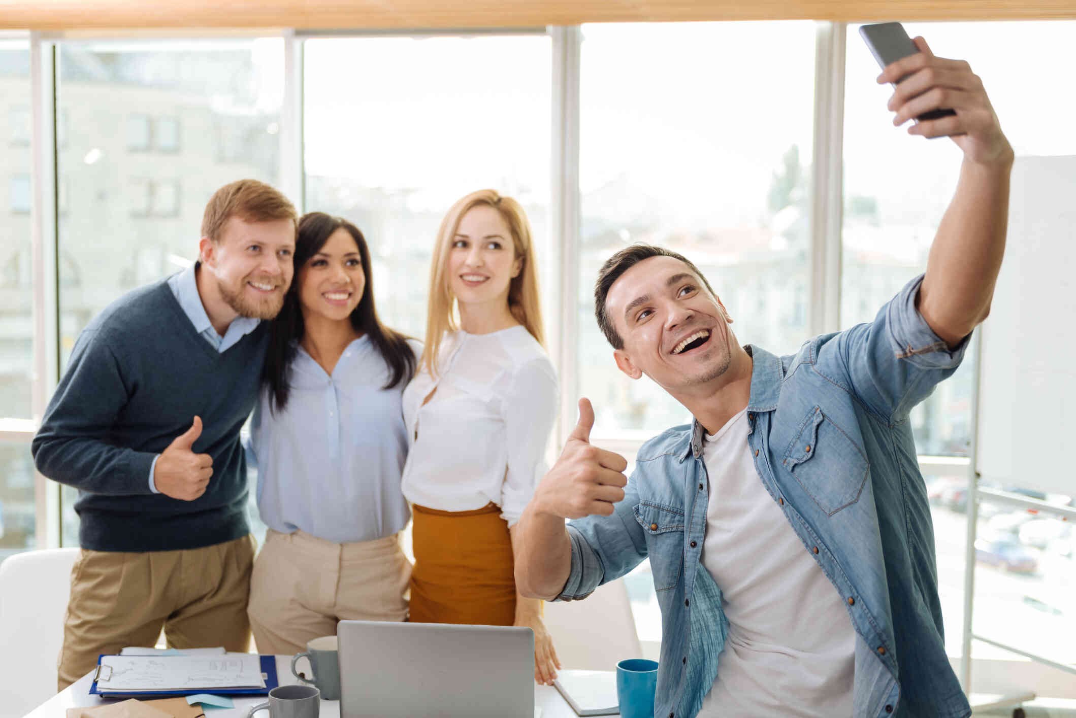 A group of people gather together and smile while taking a selfie 